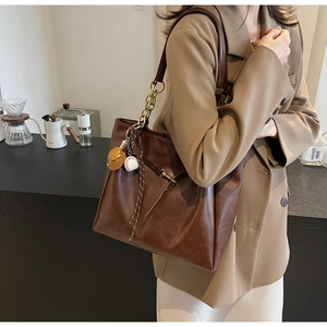 Detail view of brown PU leather tote bag with metal chain and cute decorative charms
