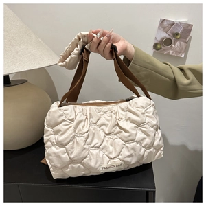 Detail view of quilted cream shoulder bag with brown zipper and fashion label