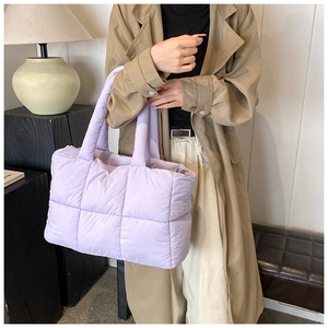 Detail of purple quilted shoulder bag showing large checkered pattern and soft fabric