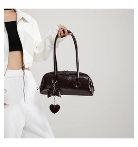 Detail of a dark brown oil wax leather shoulder bag featuring a stylish black bow accent