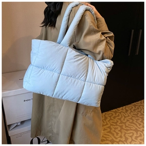 Detail of light blue quilted puffer tote bag featuring soft nylon texture and grid stitching