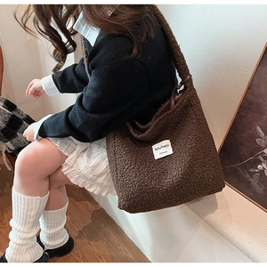 Detail of plush brown lamb wool tote bag featuring leather strap and branded fabric label
