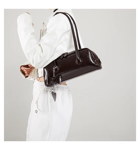 Detail of dark brown faux leather shoulder bag with chic bow and heart charm pendants
