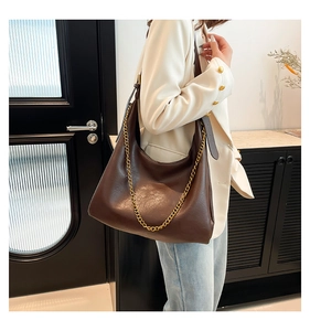 Detail of vintage dark brown PU leather tote bag with gold chain decoration