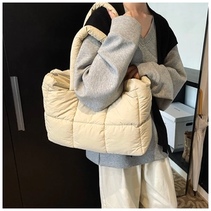 Detail of beige quilted puffer tote bag showing soft square texture and padded strap