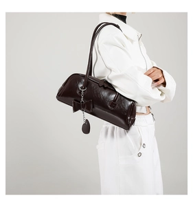 Close-up of dark brown PU leather shoulder bag with decorative bow and heart tag detail