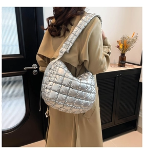 Detail of a large silver quilted puffer tote bag with adjustable wide shoulder straps