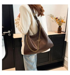 Detail of a dark brown PU leather shoulder bag featuring a gold chain and slim strap