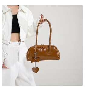 Detail view of caramel brown PU leather bag with bow accent and heart pendant