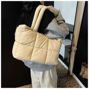 Detail view of large beige quilted tote bag showing padded straps and soft nylon texture