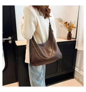 Detail of a brown PU leather hobo bag with a decorative gold chain and elegant shoulder strap