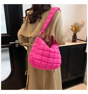Model wearing a rose red quilted puffer shoulder bag with soft padded texture