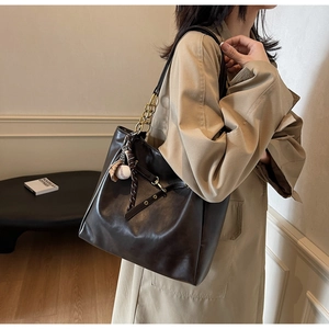 Detail view of dark brown PU leather tote bag with gold chain strap and baseball pendant