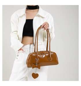 Brown faux leather handbag featuring long top handles and decorative heart-shaped charms