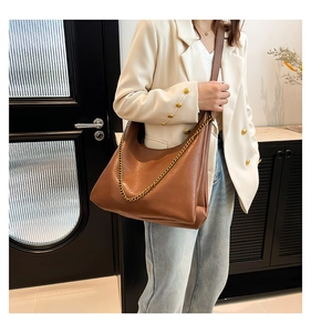 Detail of stylish brown PU leather shoulder bag with gold chain and crinkled texture