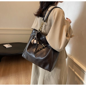 Detail shot of deep brown PU leather tote bag with metal chain and sports charms