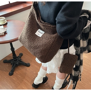 Detail of dark brown faux shearling hobo bag with matching mini coin purse and white patch