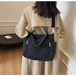 Detail view of black quilted shoulder bag featuring rhombic stitching and metal hardware