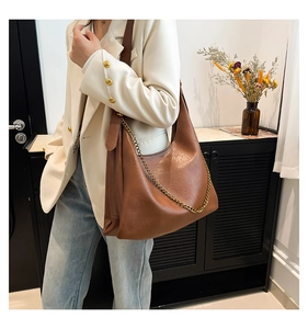 Detail of a brown PU leather tote bag with golden chain and pebble grain texture
