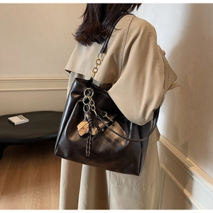 Detail of dark brown faux leather tote bag with gold hardware and baseball glove charm