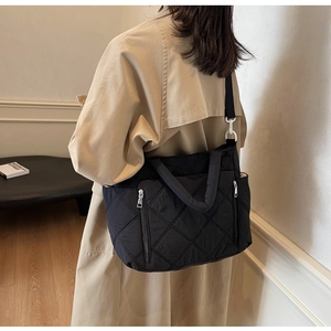 Rear view of a black quilted nylon crossbody bag with diamond stitch detail on model