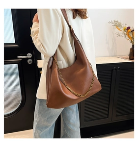 Detail of vintage brown PU leather shoulder bag with decorative chunky gold chain accent