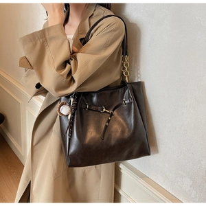 Detail of coffee brown PU leather tote bag with gold chain strap and baseball pendant