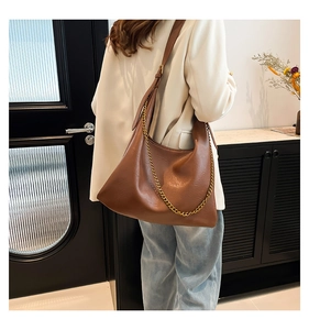 Close-up of caramel brown PU leather hobo bag with gold chain strap and broad shoulder strap