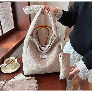 Detail of off-white sherpa tote bag with logo patch and matching pouch in cozy setting