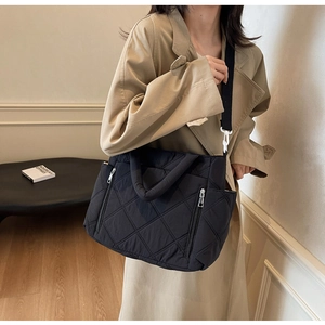 Detail of black quilted nylon tote bag with dual zipper pockets and wide shoulder strap