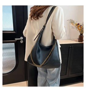 Close-up of black PU leather shoulder bag with gold chain detail and adjustable strap