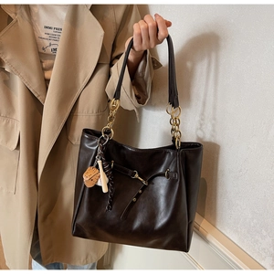 Detail of dark chocolate PU leather tote with gold chain strap and baseball charms
