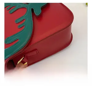 Dettaglio delle cuciture sul fondo e fibbia dorata su una borsa natalizia in pelle rossa