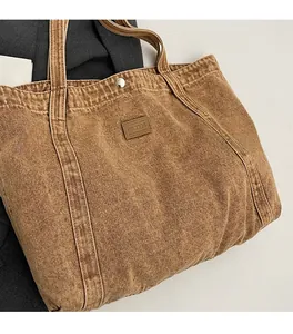 Detail of vintage washed canvas tote bag with leather logo patch and metal snap closure