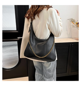 Detail showing high-quality black PU leather texture and thick gold chain on a hobo bag