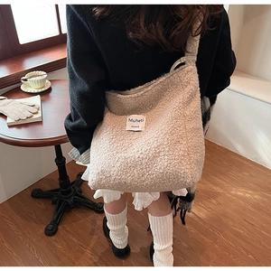 Close-up of fluffy cream crossbody bag on model in a cozy indoor cafe setting
