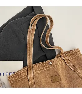 Close-up of vintage brown canvas tote bag featuring silver snap button and leather logo patch