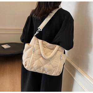 Detail view of quilted beige shoulder bag with side zipper pocket and textile strap