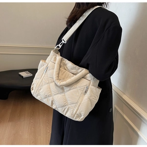 Detail view of quilted puffer tote bag in beige with shoulder strap and side pockets