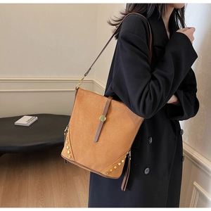 Borsa tote in camoscio marrone con borchie dorate lucide e tracolla sottile indossata