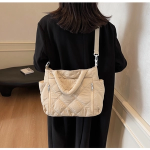 Detail of beige quilted nylon tote bag with vertical zippers and wide shoulder strap