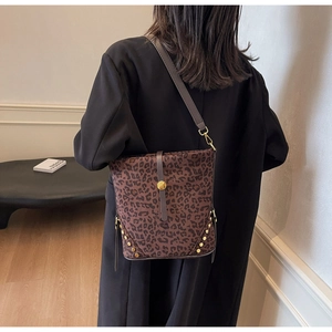 Dettaglio borsa a secchiello leopardata con fibbie dorate e rivetti metallici sul fondo