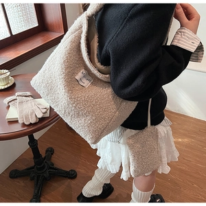 Detail of beige faux shearling tote bag set with a textured fleece finish and fabric label