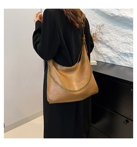 Close-up of caramel brown PU leather tote bag with stylish gold chain strap details