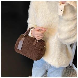 Détail d'un sac polochon en peluche marron avec anse en cuir porté par un mannequin chic