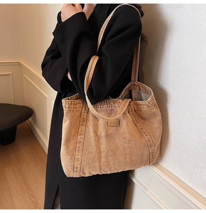 Close-up of brown washed canvas tote bag with leather logo patch and stitching detail