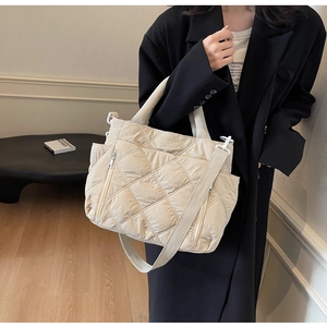 Detail view of cream quilted nylon shoulder bag with adjustable strap and side pockets