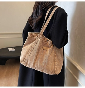 Detail of tan washed denim tote bag showing oil bag leather patch and stitching
