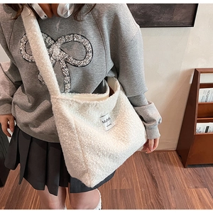 Close-up of white plush crossbody bag showing the soft fuzzy texture and woven logo tag