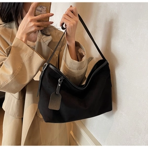 Sac à bandoulière classique en similicuir noir porté avec un trench-coat kaki élégant